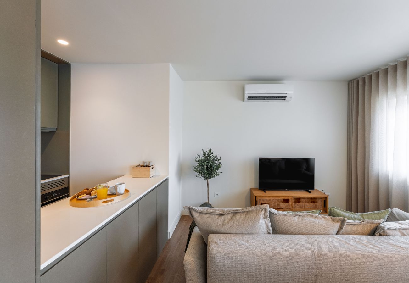 Modern living room with sofa, smart TV, and access to the balcony